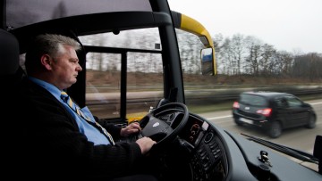 Busfahrer während der Fahrt am Lenkrad eines Busses