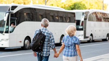 Zwei Reisende (Paar), die auf den geparkten Reisebus zugehen