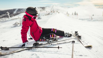 Eine Frau, die mit Skiern auf der Piste gestürzt ist