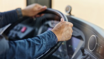 Busfahrer (Nahaufnahme) am Steuer eines Busses