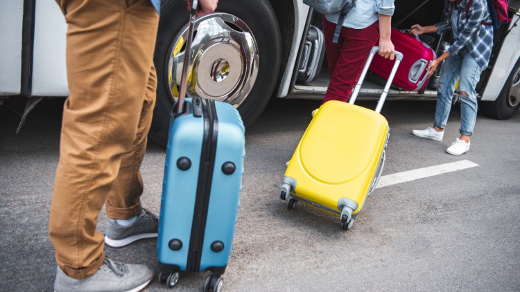 Reisende, die ihre Koffer in einen Reisebus verladen