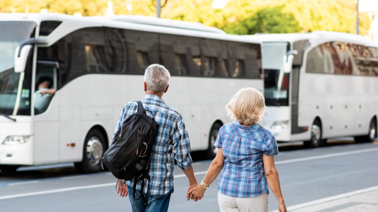 Zwei Reisende (Paar), die auf den geparkten Reisebus zugehen